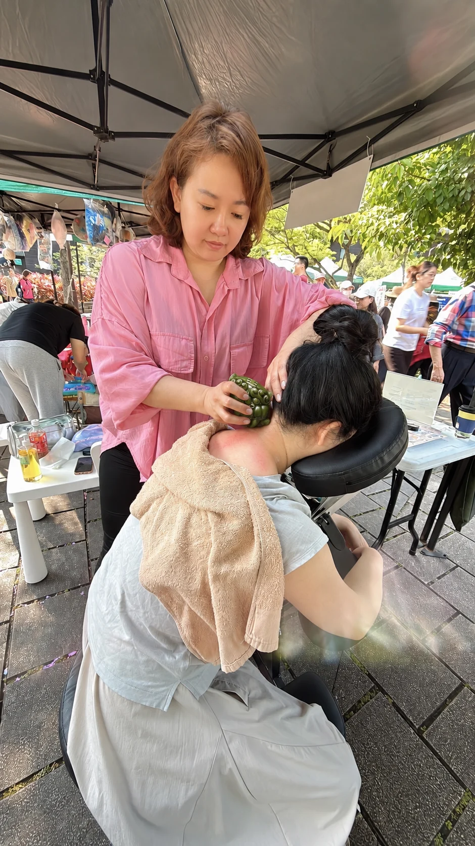 市集攤位上用刮痧球為客人做極速肩頸放鬆